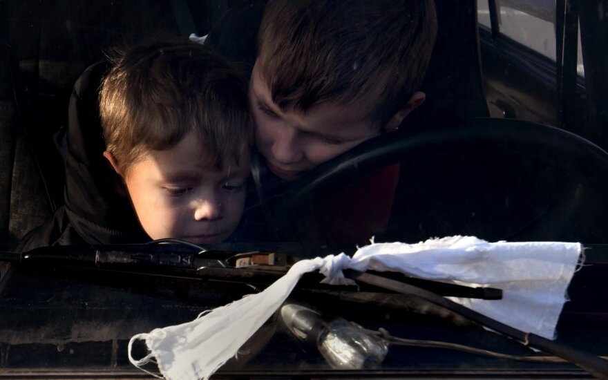 Iš Sartanos, Donetsko regiono kilę Artūras ir Natalija  bei jų vaikai Saša, Vova ir Katya laukia tranzitiniame humanitarinės pagalbos sustojime. Nuotrauka daryta Ukrainos gyventojams bėgant į Zaporižią nuo beviltiškai žiaurių gyvenimo sąlygų Rusijos okupuotame Mariupolyje. Pabėgėliai evakuojasi sudaužytais automobiliai, ant kurių užrišti balti raiščiai ir užrašyta „vaikai“. 2022 kovo 28 d., Ukraina. 